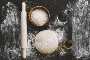 Raw yeast dough for pizza, bread or pasta. Dark food background. Copy space for text